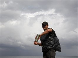 A Cuban migrant shaves his beard as others freshen up after they crossed the...