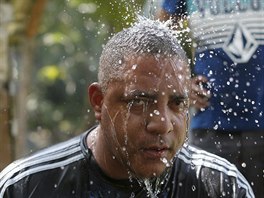 A Cuban migrant shaves his beard as others freshen up after they crossed the...