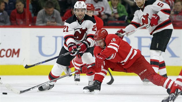 Elias Lindholm (v ervenm) z Caroliny se natahuje po puku, brn ho Kyle Palmieri z New Jersey.