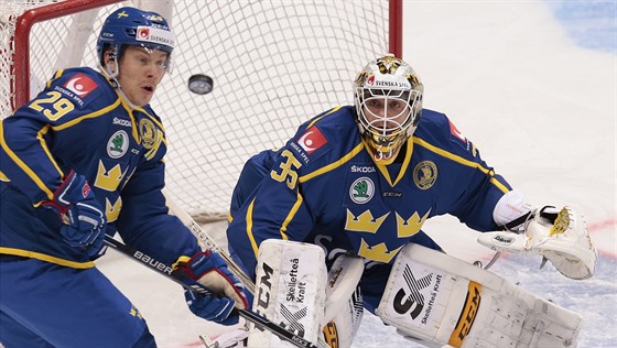 Erik Gustafsson (vlevo) a védský gólman Markus Svensson pozorn sledují puk v...