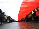 Backers of Poland's ruling conservative party carry a huge national flag as...