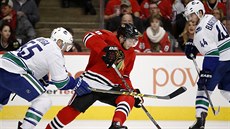 Patrick Kane z Chicaga (v erveném) se snaí projít mezi hokejisty Vancouveru.