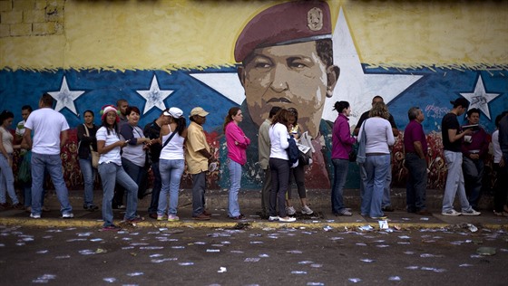 Portrét Huga Cháveze shlíží na frontu před volební místností v Caracasu (6....