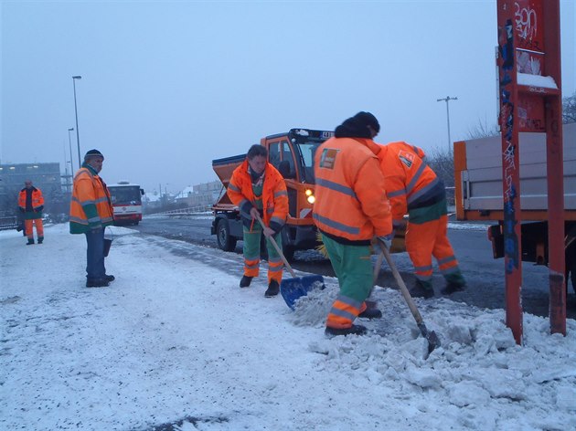 Pracovníci Pražských služeb uklízejí sníh na autobusové zastávce Strašnická.