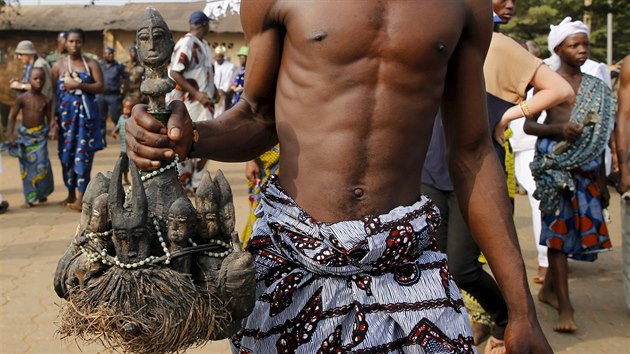 Vyznavač drží voodoo loutku při tradičním průvodu ulicemi Ouidah.