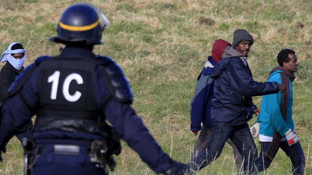 Francouzsk policista zastavuje migranty, kte se snaili dostal do nkladnch aut v nadji, e se dostanou do Britnie. (21. 1. 2016)