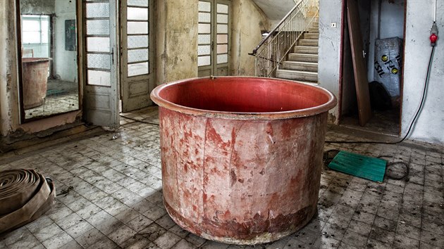 Interi�r �kroupova domu p�ipom�n� d�m hr�zy, ze st�n vis� kusy malby i tapet.