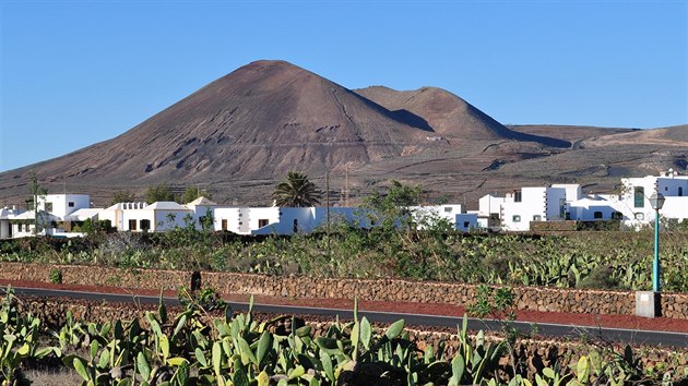 Lanzarotská klasika - silnička lemovaná kaktusy, malá vesnička s bíle natřenými domy a na pozadí přísně působící sopečný kužel. Snímek je z Guatizy na severovýchodě ostrova.