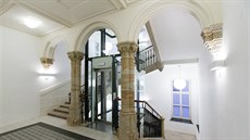 Pískovcové schodit z 19. století doplnil moderní prosklený výtah.