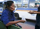 Pranom Chartyothin, a 72-year-old bus conductor, counts coins with a colleague...