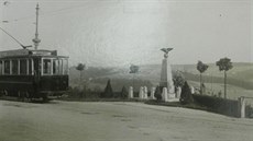Válečný památník s projíždějící tramvají.
