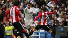Cristiano Ronaldo (v bílém) se proplétá obranou Bilbaa.