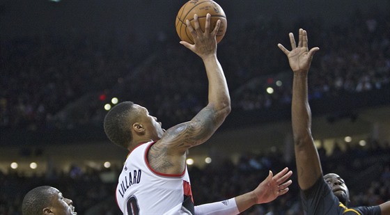 Portlandský basketbalista  Damian Lillard stílí pes bránícího Draymonda...