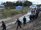Dělníky rozebírající přístřešky migrantů v Calais chrání zástupy policistů s...
