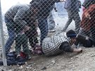 Uprchlíci podlézají plot krátce poté, co makedontí policisté pouili slzný...