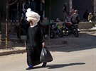 ena na hlav nese chléb. Jde po ulici v rebely obsazovaném mst al-Gharbiyah...
