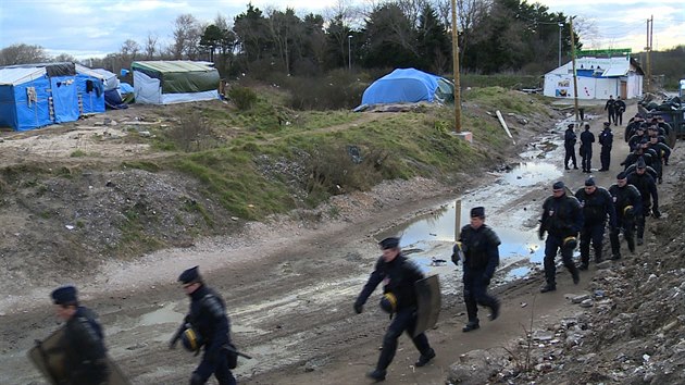 Dělníky rozebírající přístřešky migrantů v Calais chrání zástupy policistů s přilbami a štíty (29. února 2016)