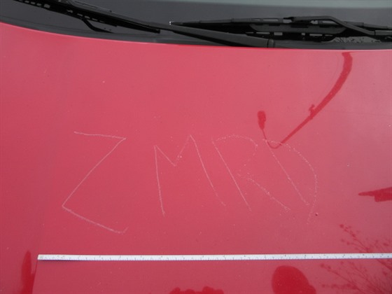 Hanlivý nápis na kapotě auta.