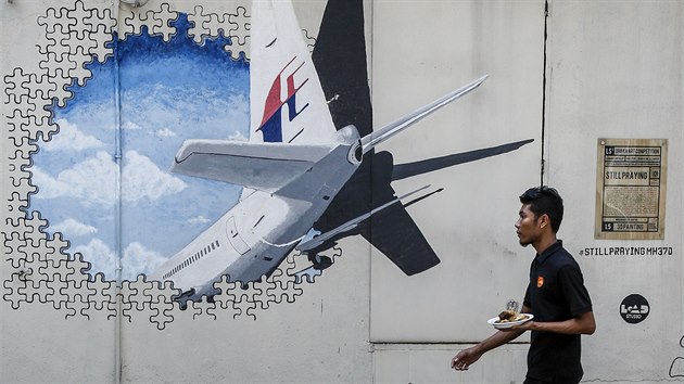 Malba na zdi v Malajsii, znázorňující let MH370. „Stále se modlíme“, hlásá plakát vpravo (23. února 2016)