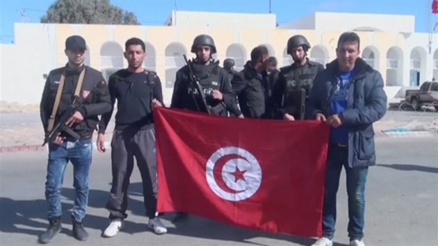Policist se fot s tuniskou vlajkou po odraen toku dihdist ve mst Binkardn (7. bezna 2016).