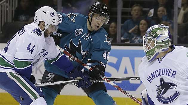 Tom Hertl (uptosted) ze San Jose v souboji s vancouverskm Mattem Bartkowskim. Ve sleduje glman Jacob Markstrm.