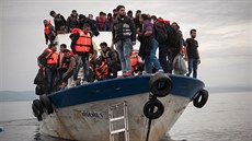 Uprchlíci a běženci na turecké lodi, která právě připlouvá k břehům řeckého...
