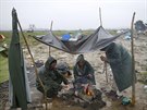 Benci se ohívají u ohn v provizorním táboe na hranici ecka a Makedonie...