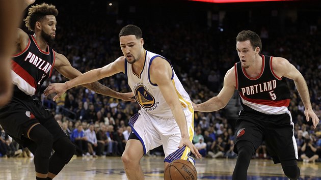 Klay Thompson (uprosted) z Golden State prohn Allena Crabbea (vlevo) a Pata Connaughtona z Portlandu.