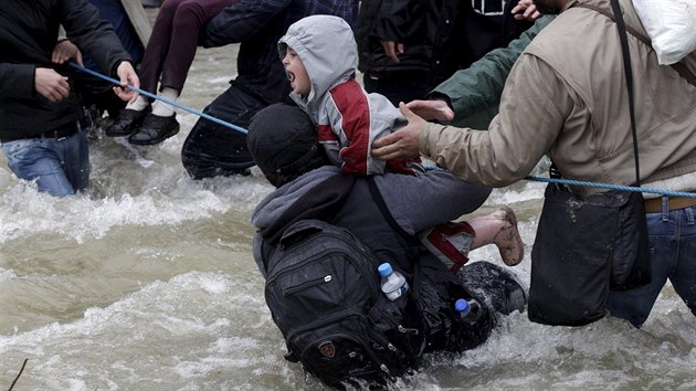 Lid se sna zachrnit dt pi pechodu eky na makedonsko-eck hranici, kterou v pondl pekroilo pes dva tisce uprchlk z tbora v eckm Idomeni (14. bezna 2016).