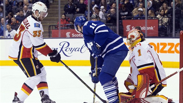 Zach Hyman (v modrm) z Toronta se ocitl ped brankem Jonasem Hillerem z Calgary. Ubrnit se ho pokou Jakub Nakldal.