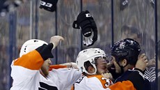 Ryan White (vlevo) a Radko Gudas z Philadelphie se vrhají na Jareda Bolla z...