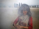 Dívka v uprchlickém táboe Idomeni pivírá oi ped kouem. (1. dubna 2016)