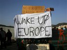 Demonstranti na ostrově Lesbos nesou transparent s nápisem „Probuď se, Evropo“....