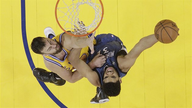 Karl-Anthony Towns (vpravo) z Minnesoty hrne m do koe Golden State, zastavit se ho sna Andrew Bogut.