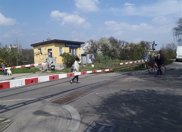 Chodci přecházejí přes přejezd ve Veleslavíně, přestože jsou stažené závory.