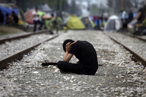 Jeden z uprchlík posedává na trati u hranic ecka a Makedonie (19. dubna 2016)