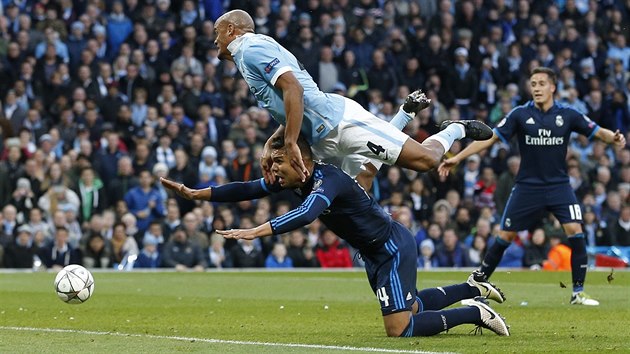 Vincent Kompany z Manchesteru City fauluje v hlavikovm souboji s Casemirem z Realu Madrid.