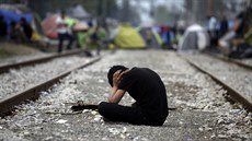 Jeden z uprchlík posedává na trati u hranic ecka a Makedonie (19. dubna 2016)