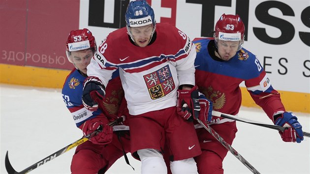 Český hokejista David Pastrňák (uprostřed) bránený Alexejem Marčenkem (vlevo) a Jevgenijem Dadonovem z Ruska.