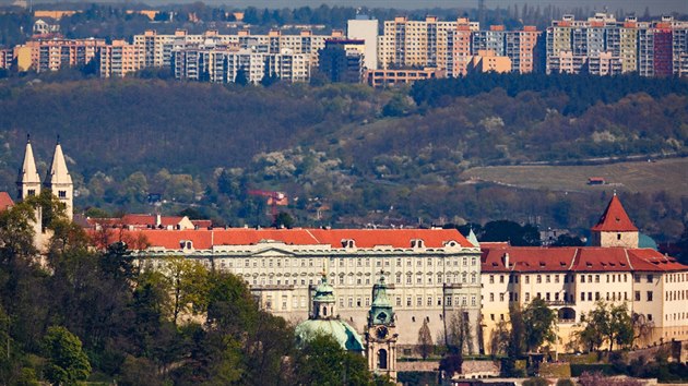 Pohled na Pražský hrad, v pozadí trojská stráň a sídliště Bohnice; v popředí vykukuje nad stromy střecha kostela sv. Mikuláše na Malostranském náměstí.