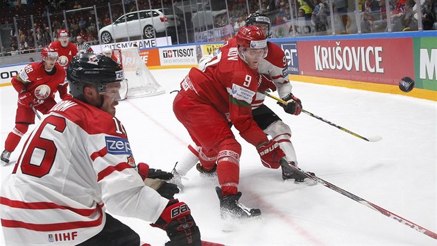 Kanadsk hokejista Max Domi (vlevo) bojue o puk s Romanem Djukovem z Bloruska.