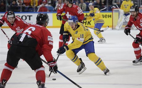 védský hokejista Mikael Backlund kontroluje puk v duelu se výcarskem.