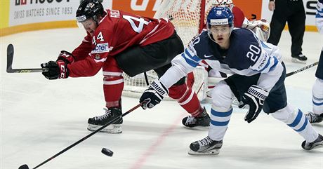 Finský hokejista Sebastian Aho (s íslem 20) bojuje o puk s Kanaanem Morganem...