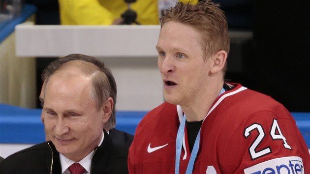 Kanadský hokejista Corey Perry hrdě pózuje s trofejí pro mistry světa, vlevo je ruský prezident Vladimir Putin.
