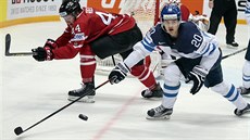 Finský hokejista Sebastian Aho (s číslem 20) bojuje o puk s Kanaďanem Morganem...