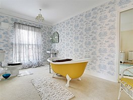 Jedna ze tří koupelen v domě má jasně žlutou samostatně stojící vanu, další je...
