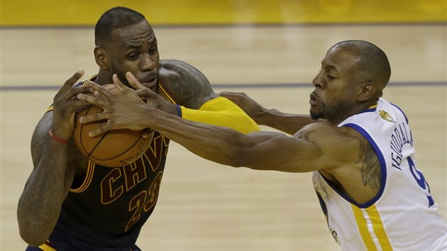 LeBron James (vlevo) z Clevelandu el obrannmu tlaku Andreho Iguodaly z Golden State.