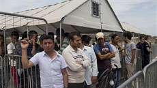 Migranti žijící v táboře na letišti Hellenikon v Aténách čekají na registraci k...
