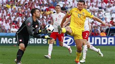 Polský branká Lukasz Fabianski zasahuje ped dotírajícím ukrajinským obráncem...