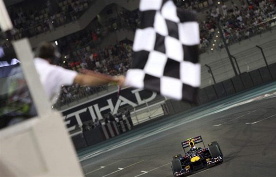 Cíl závodu formule 1 s achovnicovým praporem. Vítzí Vettel z Red Bullu.